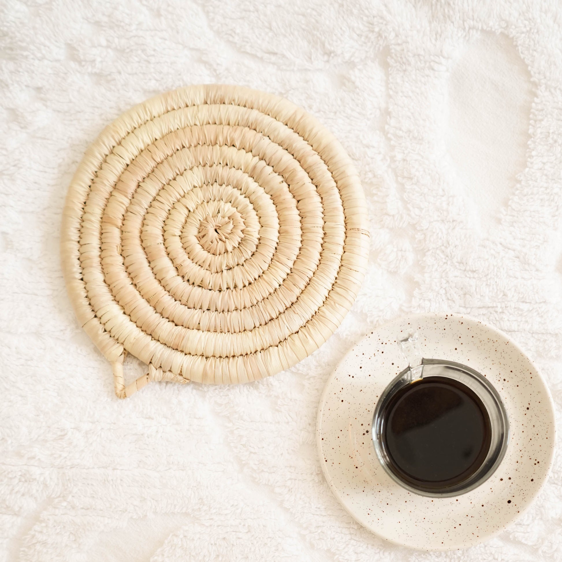 Straw trivet on top of a white table linen